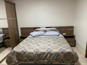 um quarto com uma cama com um cobertor e almofadas em Sobrado Oktober com Piscina em Santa Cruz do Sul