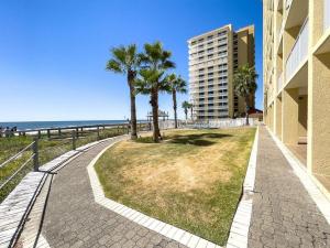 einen Fußweg nahe dem Strand mit Palmen und einem Gebäude in der Unterkunft Summer House 1006a condo in Orange Beach