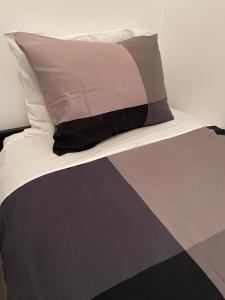 a bed with a black and gray comforter and a pillow at Modern apartment with garden in Antwerp, 15min from City center in Antwerp