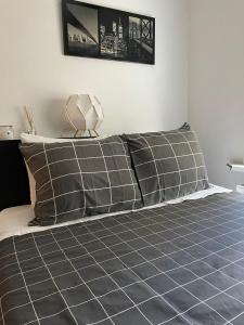 a bed with gray and white pillows on it at Modern apartment with garden in Antwerp, 15min from City center in Antwerp