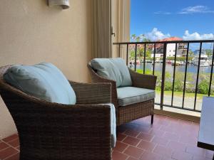 a wicker chair with a pillow sitting on a balcony at Sapphire Beach Villa Ocean and Marina View in St Thomas