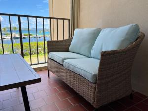 a wicker couch sitting on a balcony with a table at Sapphire Beach Villa Ocean and Marina View in St Thomas