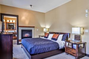 1 dormitorio con 1 cama y chimenea en Luxurious Condo with Spa, Steam Room hosted by Fenwick Vacation Rentals en Canmore