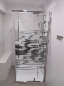 a glass shower in a bathroom with white tiles at Dom gościnny 4JAWA I in Tuczempy