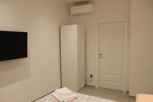 Camera bianca con porta bianca e televisore di B&B San Luca a Bologna