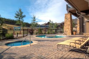 a patio with two pools and chairs and a fence at Crystal Peak Lodge 2 Bedroom Ski In, Ski Out Slopeside Condo At The Base Of Peak 7 in Breckenridge
