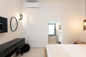 a white bedroom with a bed and a mirror at Kalopsia Home in Rethymno Town