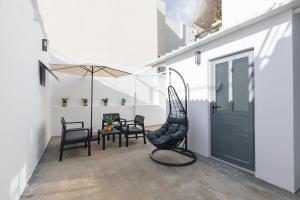 um pátio com uma cadeira, uma mesa e um guarda-chuva em Kalopsia Home em Rethymno Town