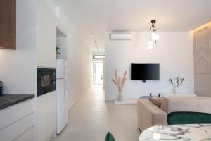 a white living room with a couch and a tv at Kalopsia Home in Rethymno