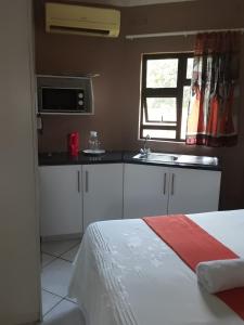 a bedroom with a bed and a kitchen with a sink at Mavundla guest house in Richards Bay