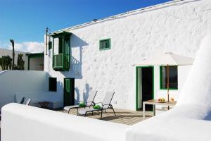a white building with a patio with chairs and an umbrella at Typical Canarian house with fabulous sea views in Tías