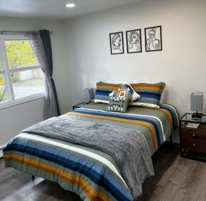 a bedroom with a bed with striped sheets and a window at Anchorage midtown apartment- Wyoming 1 in Anchorage