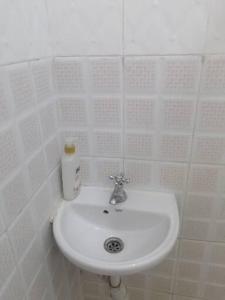 a white sink in a white tiled bathroom at Mombasa City Center Studio in Mombasa