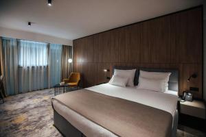 a hotel room with a large bed and a chair at City Hotel Dubrovnik in Dubrovnik