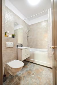 a bathroom with a toilet and a sink and a tub at UpTown Apartments in Iaşi