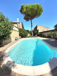 una gran piscina azul con un árbol en el fondo en La pause sous le pin en Capestang