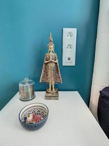 una pequeña estatua en una mesa junto a un bol de fruta en STUDIO COSY HYPER CENTRE GARE AMIENS WIFI NETFLIX 2 PERS, en Amiens