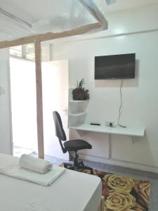 a bedroom with a bed and a chair and a television at Mombasa City Center Studio in Mombasa