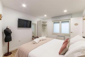 a white bedroom with a large bed and a flat screen tv at Apt in the Old Town with cool Terrace!! Private Parking in Bilbao