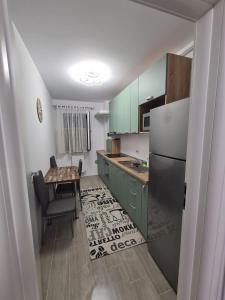 La cuisine est équipée d'armoires vertes, d'une table et d'un réfrigérateur. dans l'établissement Ghencea Residence 158 L2, à Bucarest