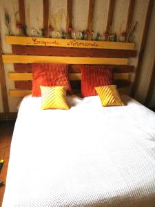 a bedroom with a bed with red and yellow pillows at Escapade Normande SPA in Yerville
