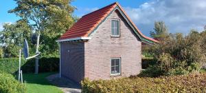 a small brick house with a red roof at Vakantiewoning de Boshoorn in Serooskerke