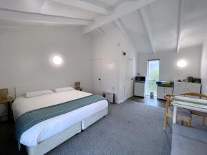 a white bedroom with a bed and a kitchen at Siesta Motel in Auckland
