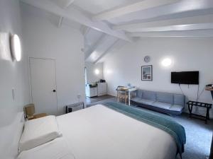 ein weißes Schlafzimmer mit einem Bett und einem Sofa in der Unterkunft Siesta Motel in Auckland