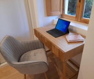 un ordinateur portable assis sur un bureau en bois avec une chaise dans l'établissement Apartamento con encanto en centro histórico Lugo -TineriaLucusHome, à Lugo