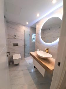 La salle de bains est pourvue d'un lavabo, de toilettes et d'un miroir. dans l'établissement Apartamento con encanto en centro histórico Lugo -TineriaLucusHome, à Lugo
