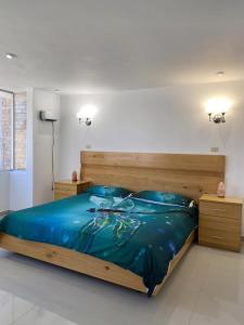 Schlafzimmer mit einem Holzbett mit blauer Bettwäsche und Kissen in der Unterkunft Hotel Casa Blanca Huacariz in Cajamarca
