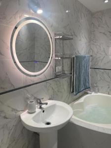 een badkamer met een wastafel, een spiegel en een bad bij Hotel Casa Blanca Huacariz in Cajamarca