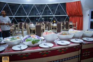 a table with bowls and plates of food on it at Jabal Rum Camp in Disah