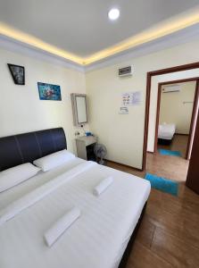 a bedroom with a large white bed and a mirror at LTH (Little Turtle's Home) in Semporna