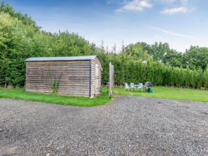 a small wooden building on a gravel road at Shepherds Hut in Biddenden