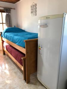 um quarto com uma cama e um frigorífico em CABAÑAS FENIX 3 5 3 4 2 3 6 2 6 3 con ARROYO NATURAL AL PIE DEL TERRENO em Villa Amancay