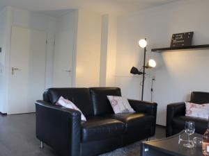 sala de estar con sofá de cuero negro y mesa en Nice holiday home 200m from the beach, en Wemeldinge