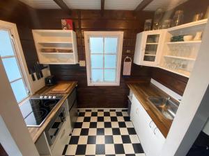 uma pequena cozinha com armários brancos e um piso xadrez em Paihia Place Cottage - central Paihia em Paihia