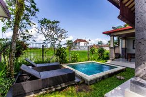 una piscina en un patio con una silla y una mesa en Villa Mandi Ubud, en Ubud