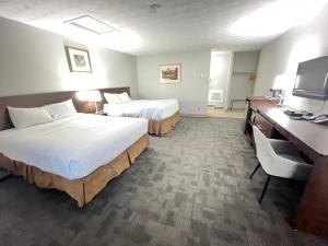 een hotelkamer met 2 bedden en een bureau bij Travelodge by Wyndham Cochrane in Cochrane