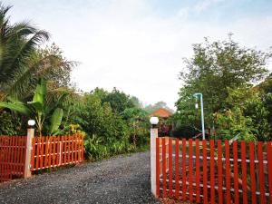 uma cerca laranja ao lado de uma estrada com árvores em ชมจันทร์รีสอร์ท ไชยา Chomjan resort 