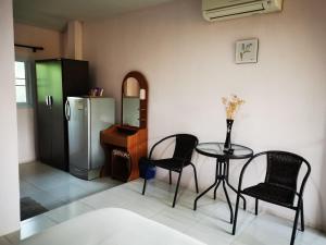 uma cozinha com uma mesa e cadeiras e um frigorífico em ชมจันทร์รีสอร์ท ไชยา Chomjan resort 