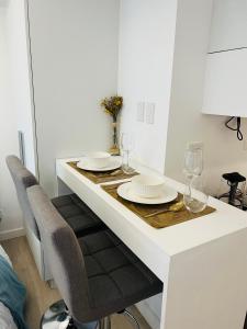 a white table with two plates and glasses on it at 2305 Azure North Residence by Cozy Lodgings in San Fernando