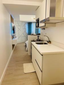 uma cozinha com balcões brancos e um lavatório num quarto em 2305 Azure North Residence by Cozy Lodgings em San Fernando