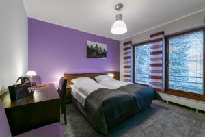 sypialnia z fioletowymi ścianami, łóżkiem i biurkiem w obiekcie CK Kalina w mieście Lądek-Zdrój