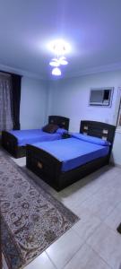 a bedroom with two beds with blue sheets and a rug at lovely 3 bedroom apartment with 2 balconies and a hot tub in Cairo