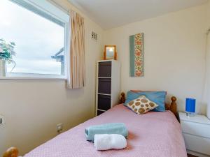 a small bedroom with a pink bed with a window at Hall Farm Bungalow in Shirley