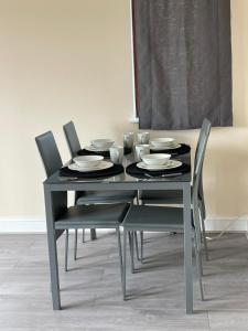a black dining table and chairs with plates and bowls at Large, Spacious 3 Bedroom Sleeps 6, Apartment for Contractors and Holidays in Lewisham, Greater London - 1 FREE PARKING SPACE & FREE WIFI in London