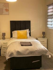 a bedroom with a bed with a black headboard and yellow pillows at Large, Spacious 3 Bedroom Sleeps 6, Apartment for Contractors and Holidays in Lewisham, Greater London - 1 FREE PARKING SPACE & FREE WIFI in London