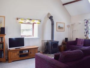a living room with a fireplace and a tv at The Byre in Westerdale